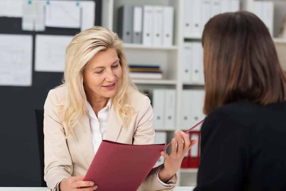 Two professional women discussing a document in an office setting.